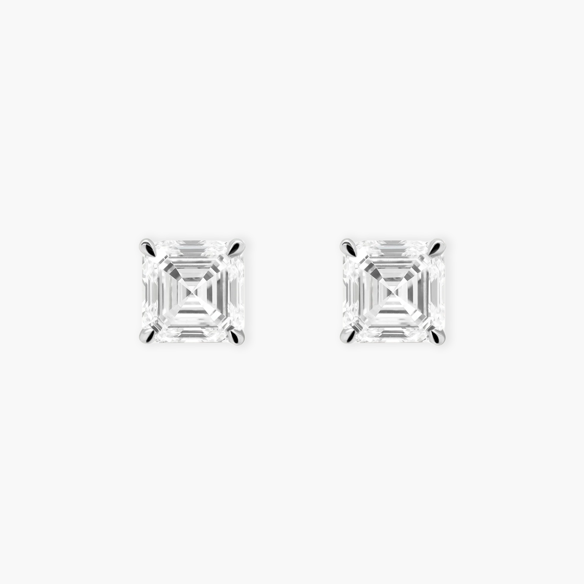 Pair of solid 18k white gold stud earrings featuring 0.38 carat Asscher cut diamonds. The earrings showcase a classic four-prong open basket setting and secure friction backs.