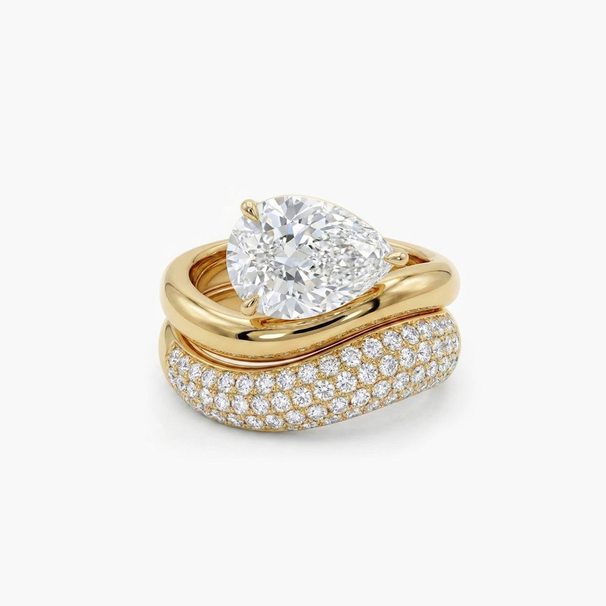 ellow gold engagement ring featuring a pear-shaped diamond set in a horizontal East-West orientation. The band features a distinct organic, wavy texture resembling molten gold, securing the diamond with a delicate three-prong setting.