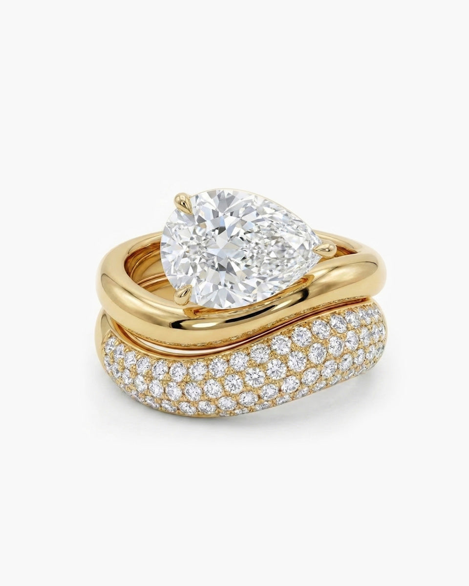 ellow gold engagement ring featuring a pear-shaped diamond set in a horizontal East-West orientation. The band features a distinct organic, wavy texture resembling molten gold, securing the diamond with a delicate three-prong setting.